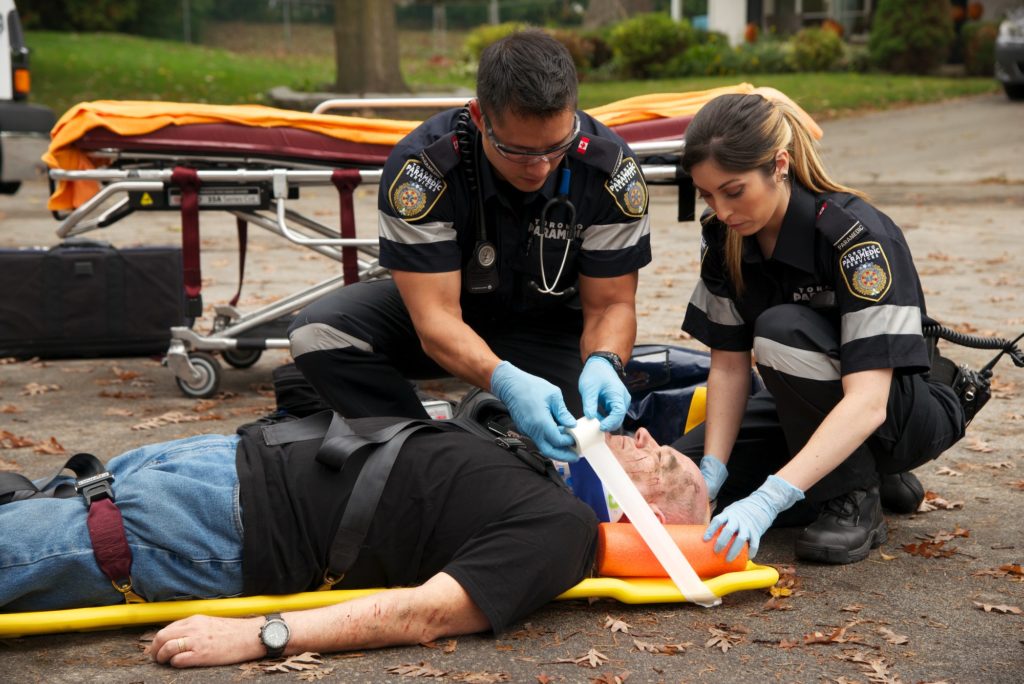 Two paramedics treating a trauma patient on a backboard outdoors
